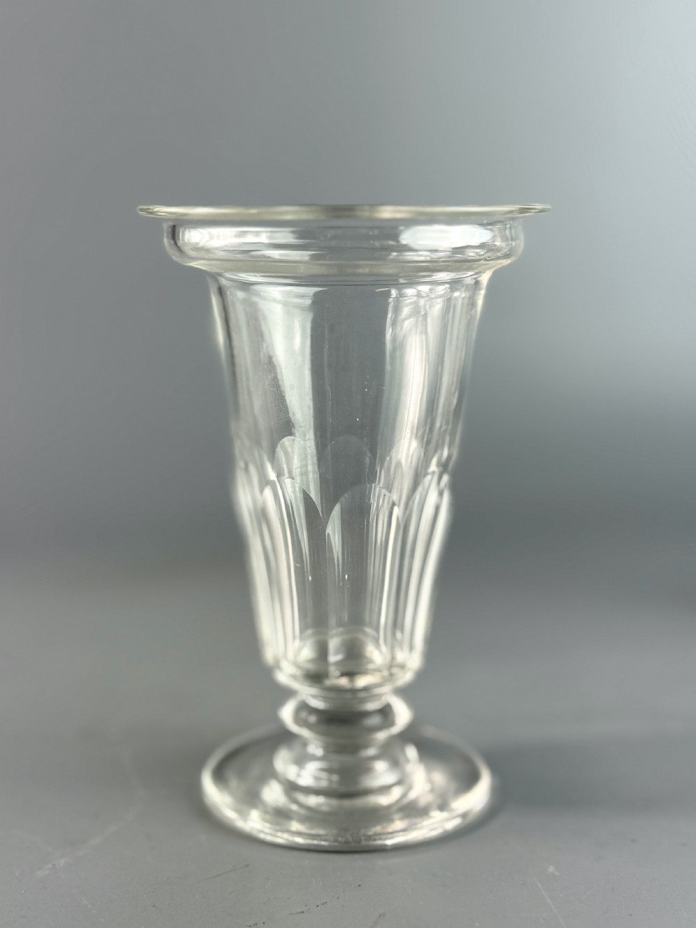 A set of six clear Georgian glass jelly cups featuring fluted tapered bowls, dish tops, knopped stems, and circular bases. View V
