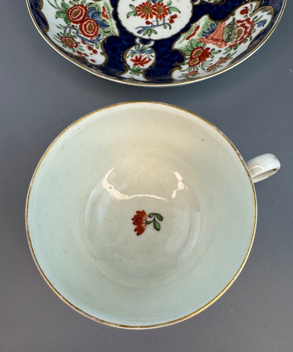 An eighteenth-century Worcester soft-paste porcelain teacup and saucer decorated with a blue scale ground and hand-painted floral cartouches. View VI