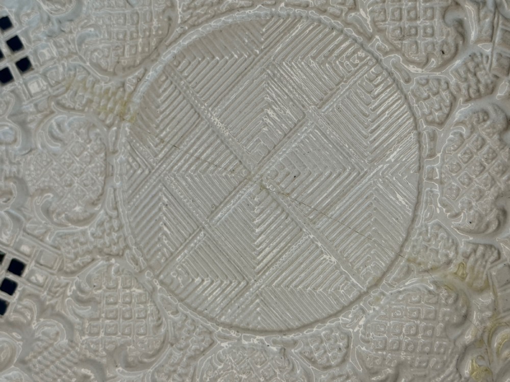 An 18th-century cream-coloured Staffordshire saltglaze stoneware lobed plate featuring lattice piercing and relief-moulded scrollwork details. View V
