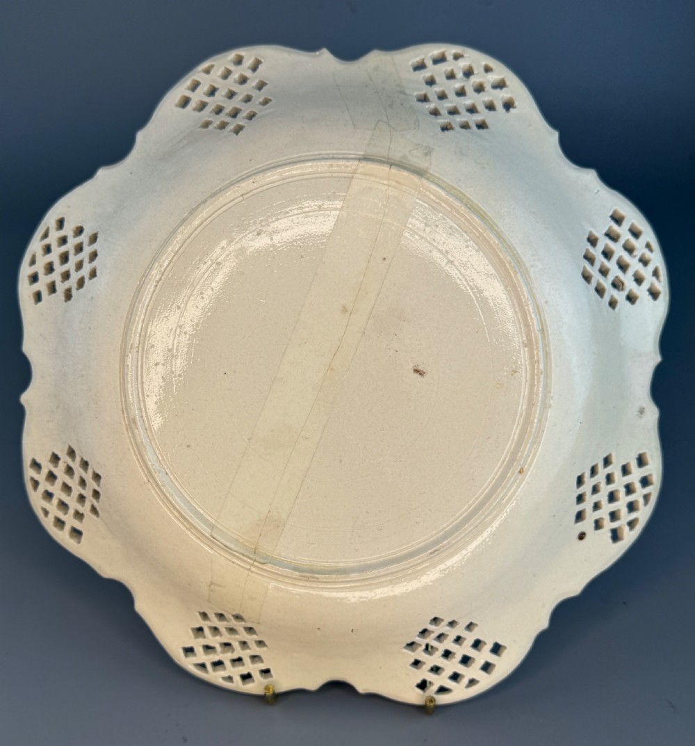 An 18th-century cream-coloured Staffordshire saltglaze stoneware lobed plate featuring lattice piercing and relief-moulded scrollwork details. View VI