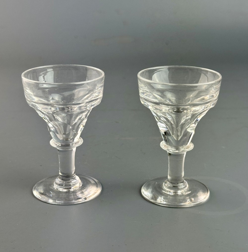 A pair of Victorian clear glass deception toasting stems featuring facet cut lower bowls and thick solid bases.