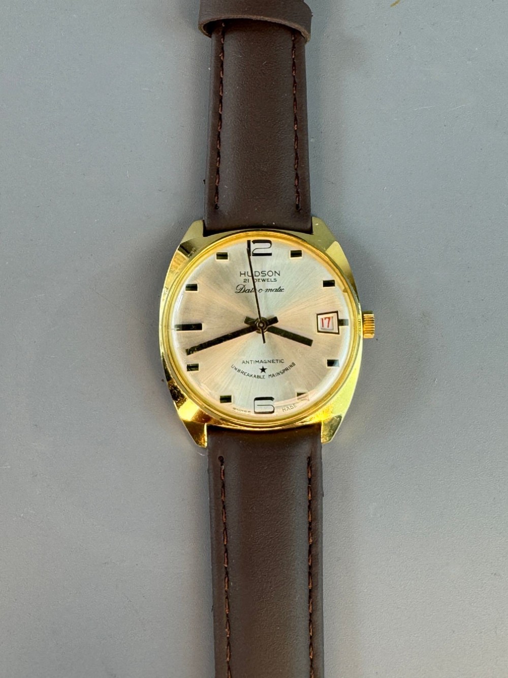 A 1960s gold-plated Hudson Date-O-Matic automatic wristwatch with a champagne dial and brown leather strap.