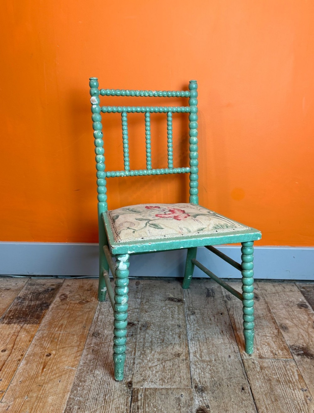 A Victorian side chair featuring a green painted bobbin-turned frame and a floral upholstered seat.