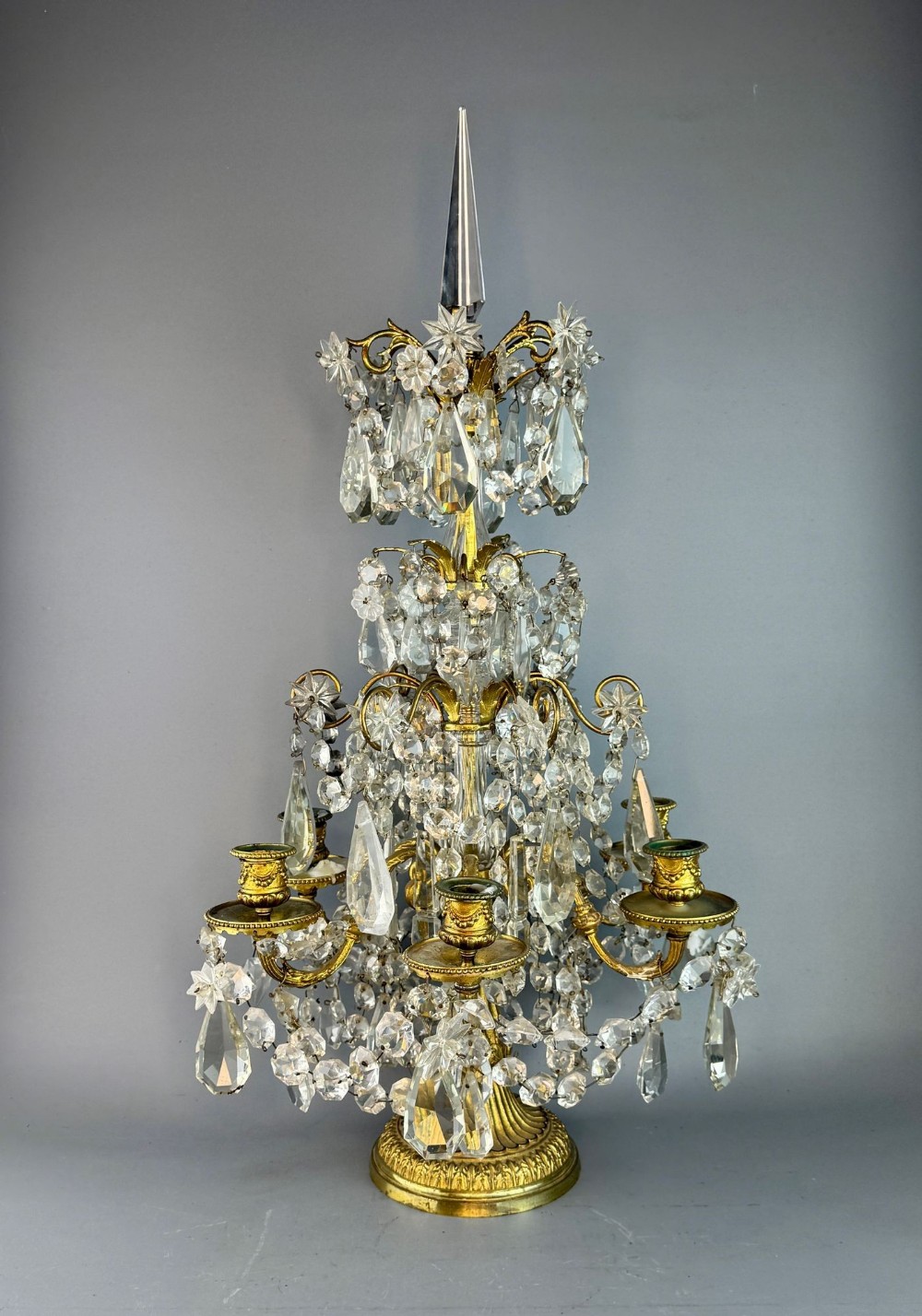 A tiered French gilt-brass candelabra decorated with multi-faceted cut glass drops and a central glass spire.
