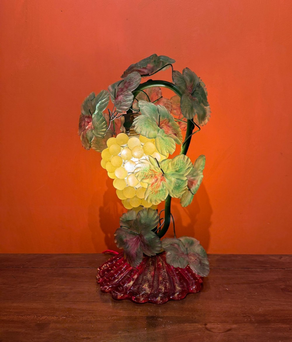 A vintage Murano glass table lamp styled as a grapevine with yellow frosted glass grapes, green glass leaves, and a fluted red glass base.