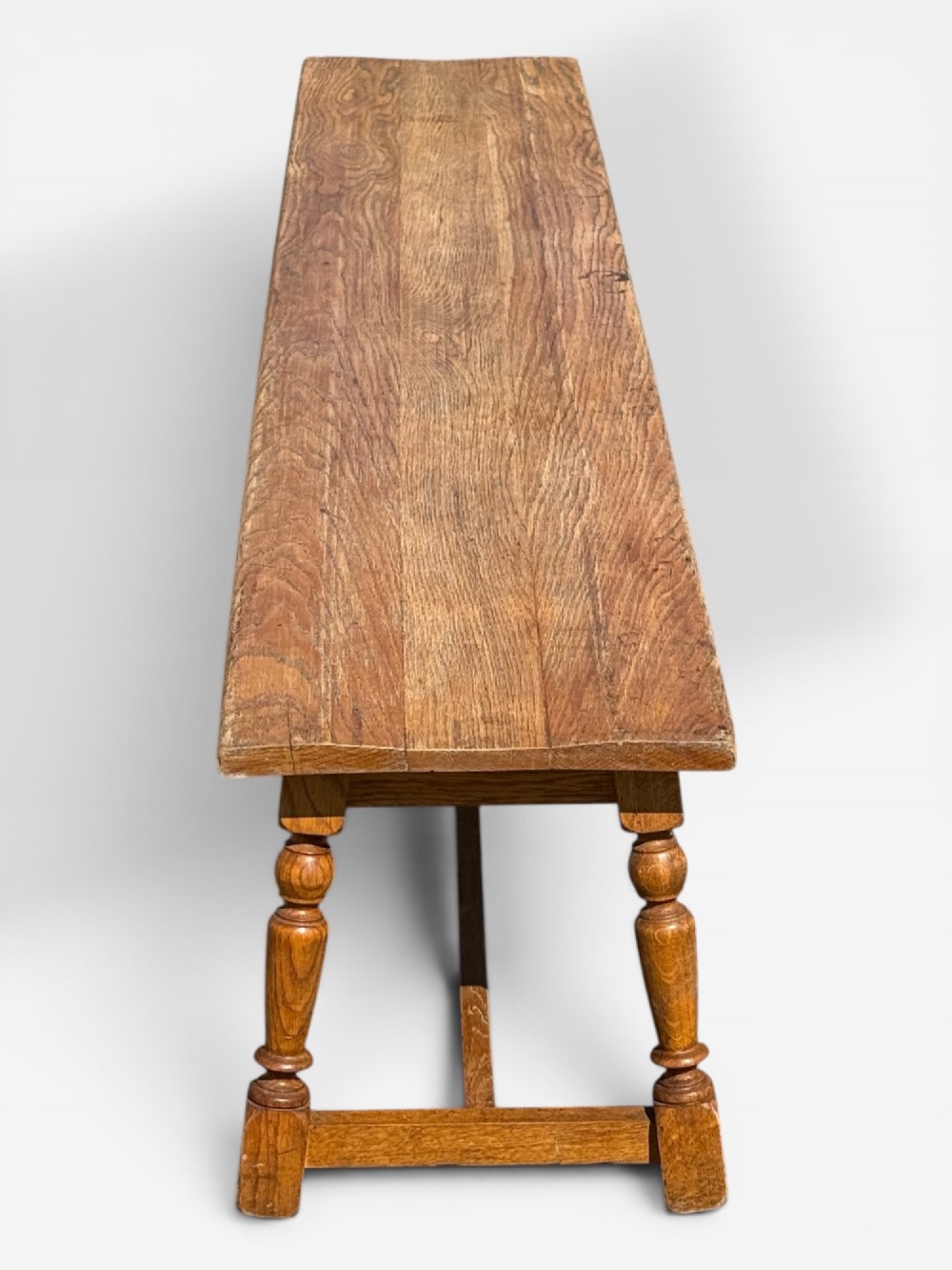 An exceptionally long rustic antique oak bench featuring a smooth rectangular seat, turned legs, and low connecting stretchers. View II