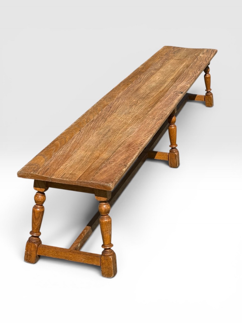 An exceptionally long rustic antique oak bench featuring a smooth rectangular seat, turned legs, and low connecting stretchers. View III