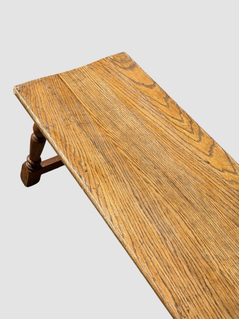An exceptionally long rustic antique oak bench featuring a smooth rectangular seat, turned legs, and low connecting stretchers. View VI