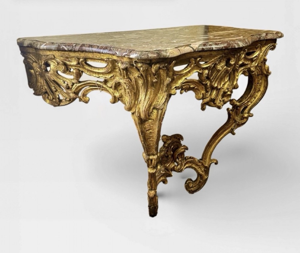 An antique Louis XV style console table featuring an intricately carved gold giltwood base with shell motifs and a contoured variegated marble top. View II