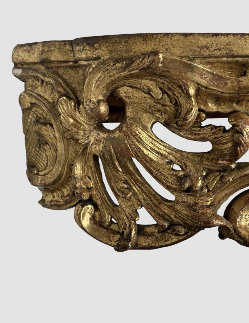 An antique Louis XV style console table featuring an intricately carved gold giltwood base with shell motifs and a contoured variegated marble top. View IV