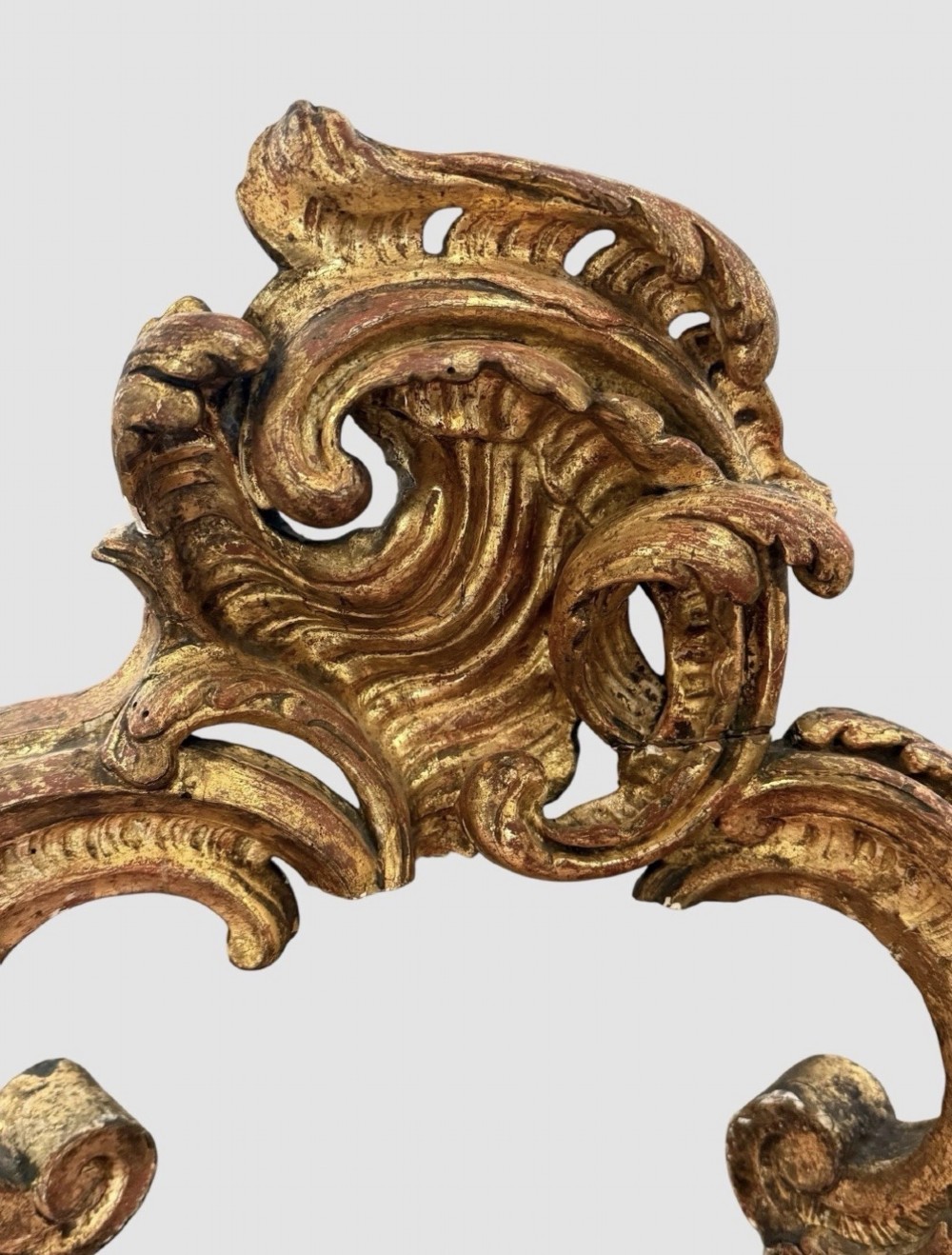An antique Louis XV style console table featuring an intricately carved gold giltwood base with shell motifs and a contoured variegated marble top. View V
