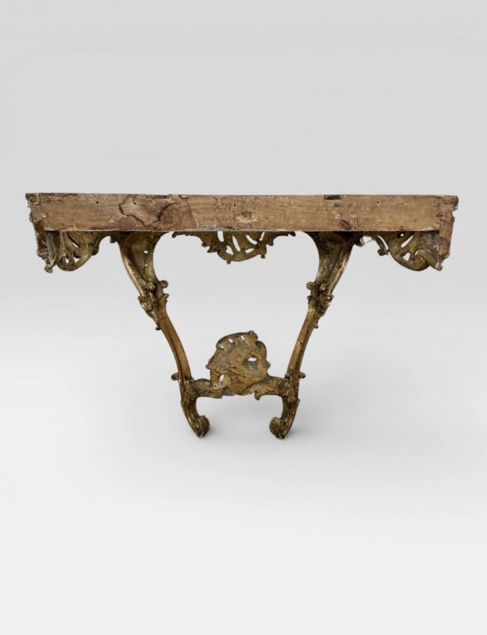 An antique Louis XV style console table featuring an intricately carved gold giltwood base with shell motifs and a contoured variegated marble top. View VII