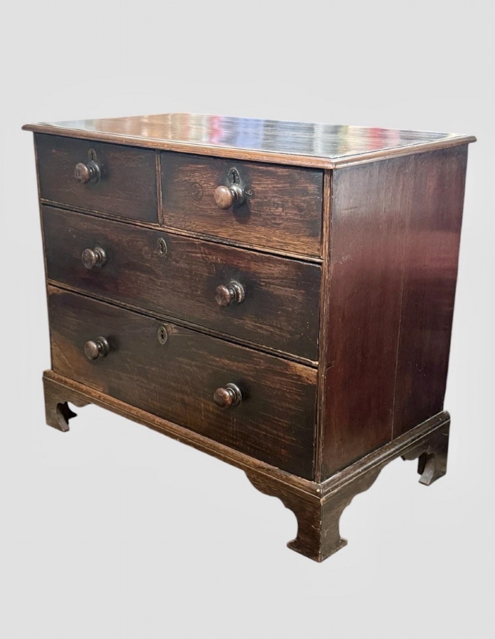 An eighteenth century dark oak chest of drawers featuring two short drawers over two long drawers with turned wooden knobs and bracket feet. View III