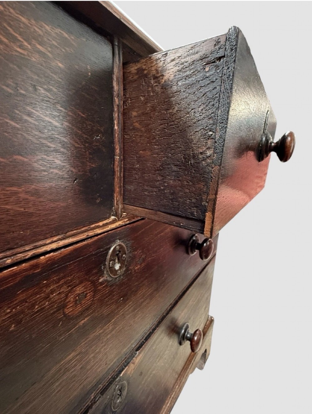 An eighteenth century dark oak chest of drawers featuring two short drawers over two long drawers with turned wooden knobs and bracket feet. View VIII