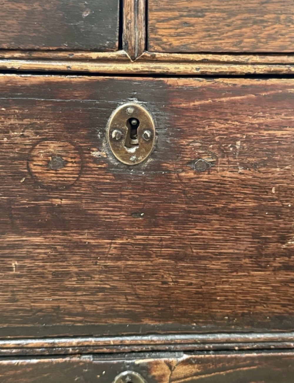 An eighteenth century dark oak chest of drawers featuring two short drawers over two long drawers with turned wooden knobs and bracket feet. View IX