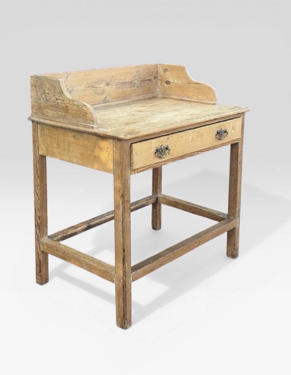 A nineteenth-century Victorian natural pine washstand featuring a raised splashback gallery, a single front drawer with brass handles, and square legs joined by a box stretcher. View II