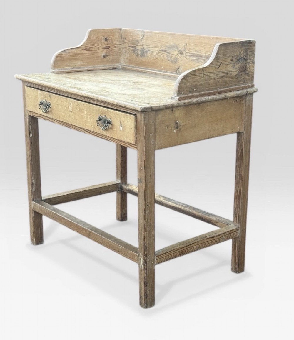 A nineteenth-century Victorian natural pine washstand featuring a raised splashback gallery, a single front drawer with brass handles, and square legs joined by a box stretcher. View III