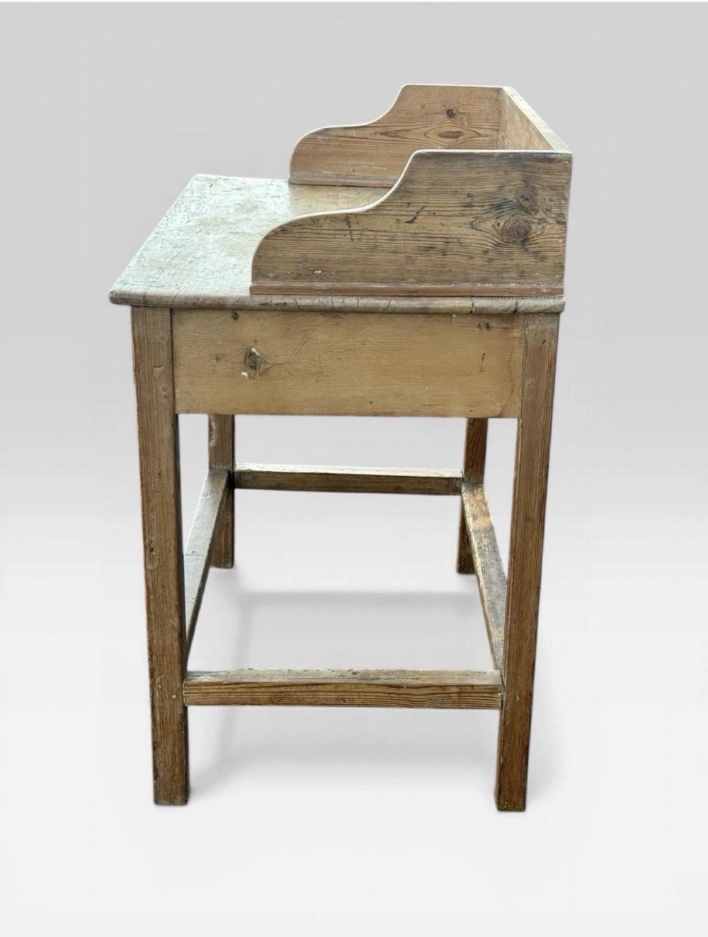 A nineteenth-century Victorian natural pine washstand featuring a raised splashback gallery, a single front drawer with brass handles, and square legs joined by a box stretcher. View V