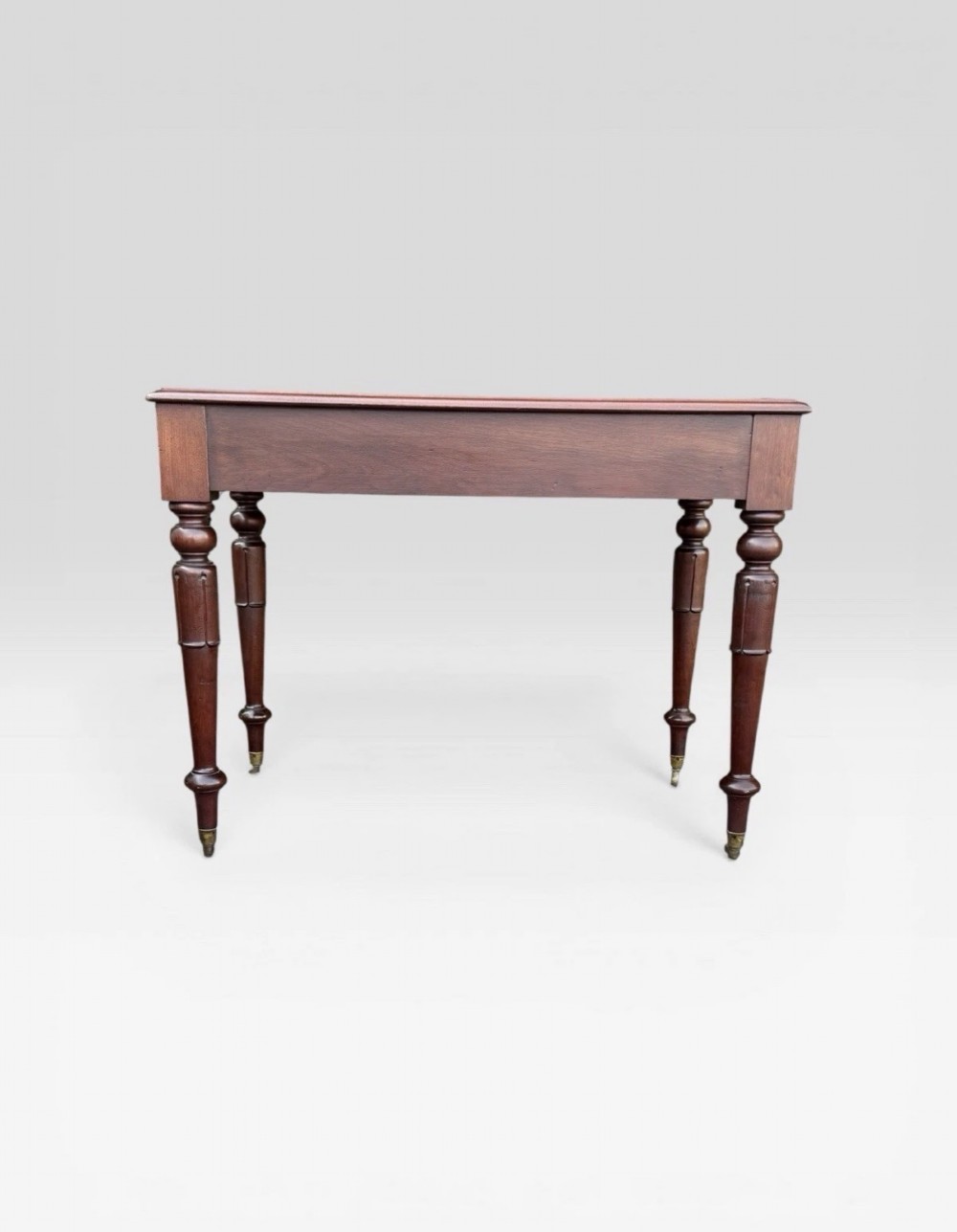 A Victorian dark mahogany side table featuring two drawers with circular wooden knobs, standing on four turned legs equipped with brass castors. View VII