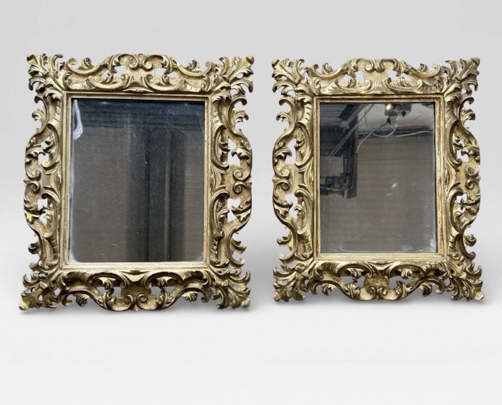 A pair of 19th-century rectangular Florentine wall mirrors featuring intricately carved giltwood frames with openwork scroll and acanthus leaf details.