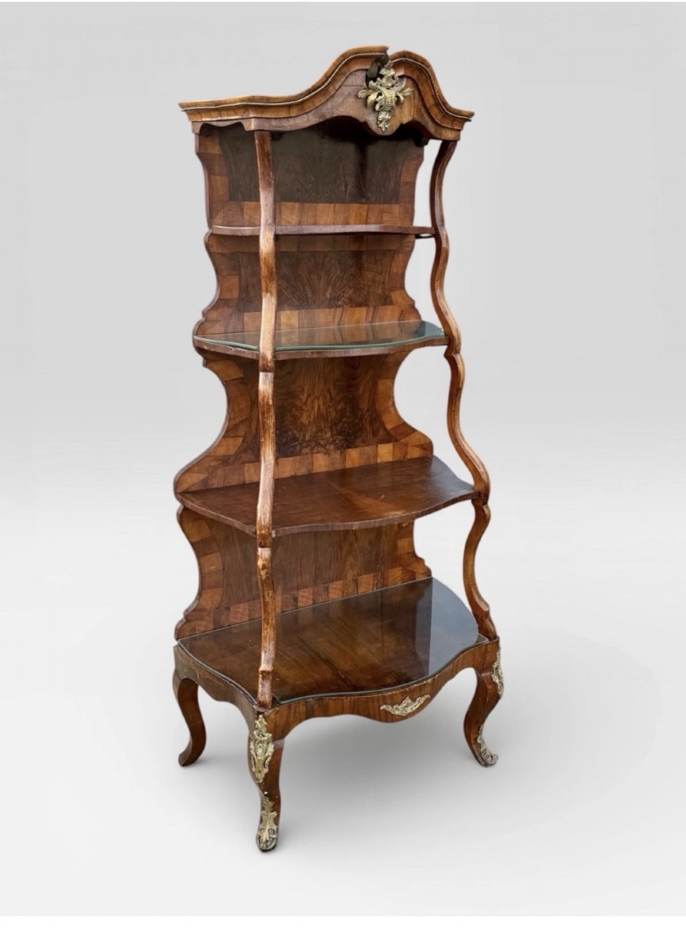 A nineteenth-century walnut etagere featuring open serpentine shelves, patterned wood veneers, ornate gilt metal mounts, and cabriole legs. View II