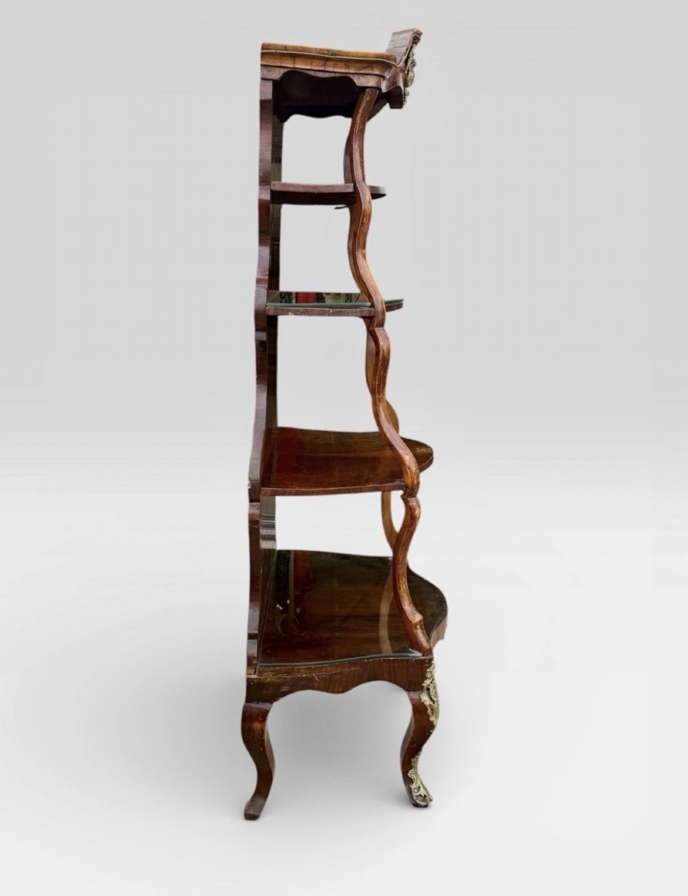 A nineteenth-century walnut etagere featuring open serpentine shelves, patterned wood veneers, ornate gilt metal mounts, and cabriole legs. View IV