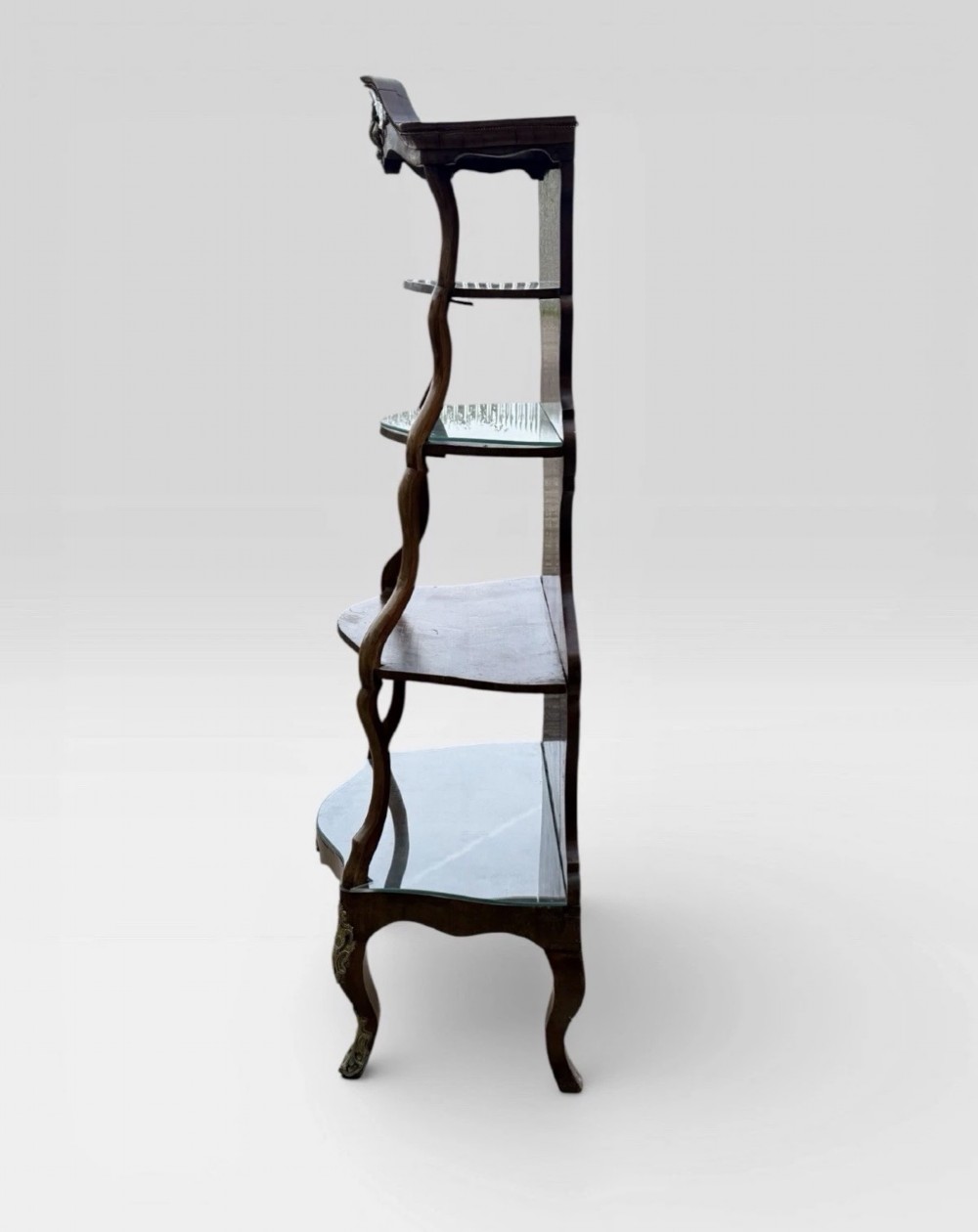 A nineteenth-century walnut etagere featuring open serpentine shelves, patterned wood veneers, ornate gilt metal mounts, and cabriole legs. View V