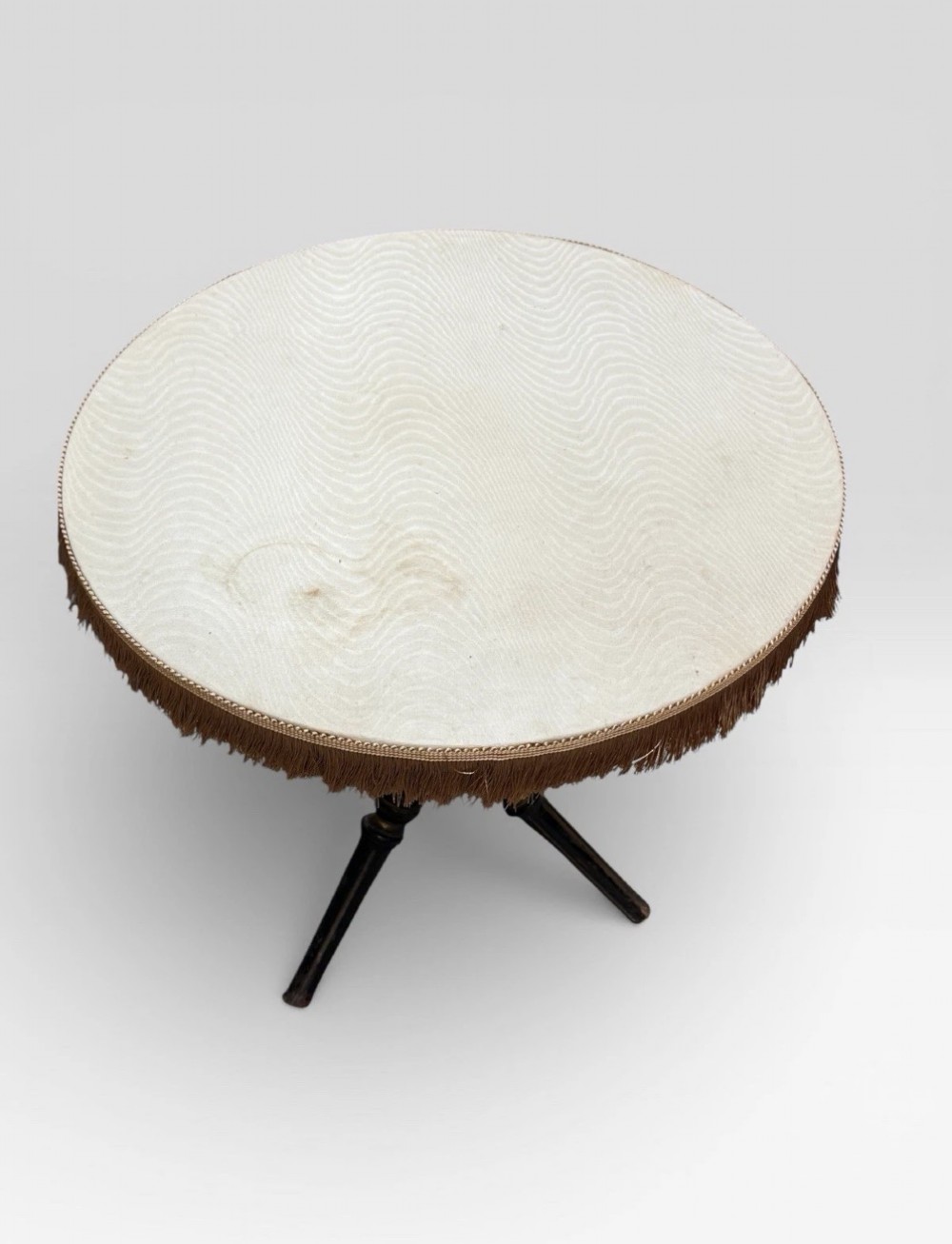 A Victorian Aesthetic Movement ebonised gypsy table with turned tripod legs, gilt highlights, and a cream fabric top with metallic fringe. View IV