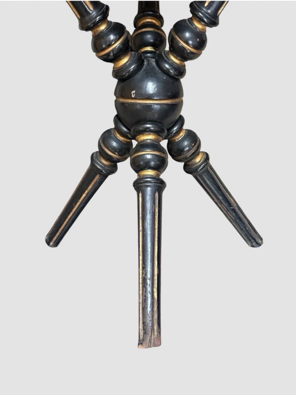 A Victorian Aesthetic Movement ebonised gypsy table with turned tripod legs, gilt highlights, and a cream fabric top with metallic fringe. View V