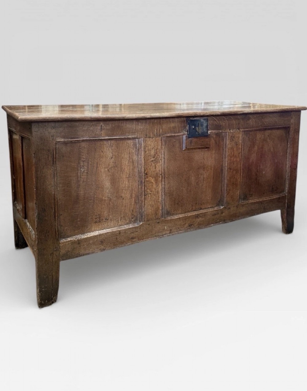 An antique 18th-century oak coffer featuring a three-panel front design and a central iron escutcheon lock plate. View II