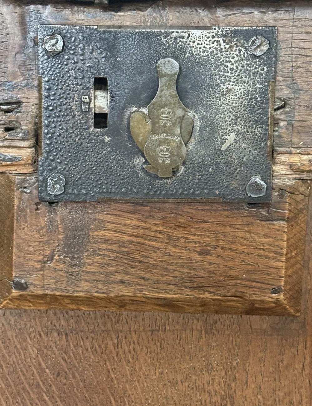 An antique 18th-century oak coffer featuring a three-panel front design and a central iron escutcheon lock plate. View VII