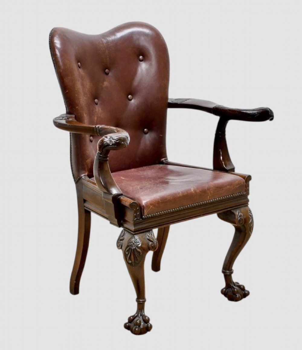 Victorian mahogany library armchair upholstered in button-backed brown leather with carved cabriole legs and claw and ball feet.