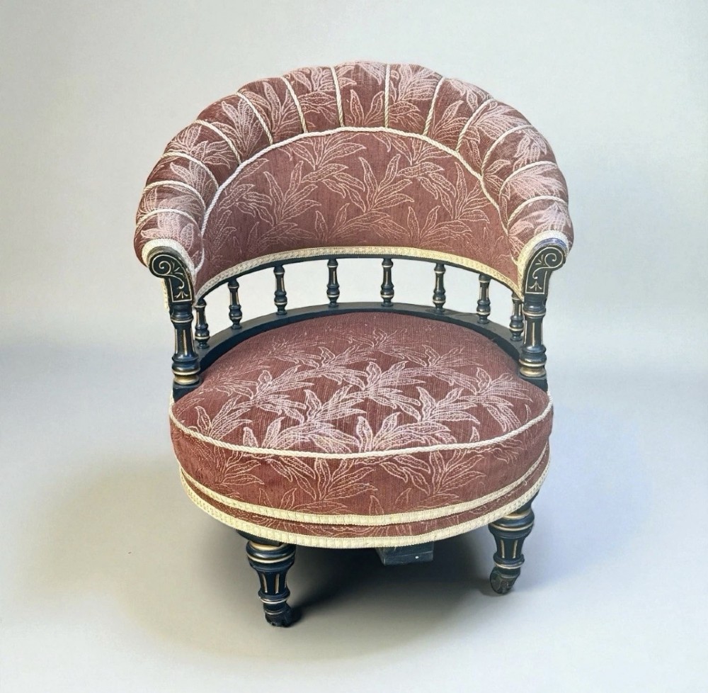A Victorian ebonised revolving armchair upholstered in terracotta leaf-patterned fabric with turned gilt-accented spindles and castor feet. View III