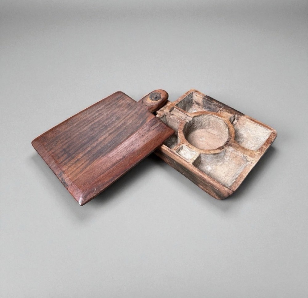 A hand-carved warm brown wooden spice box featuring a smooth grain finish and a pivoting lid held by a single metal rivet. View II