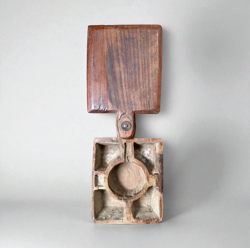A hand-carved warm brown wooden spice box featuring a smooth grain finish and a pivoting lid held by a single metal rivet. View III