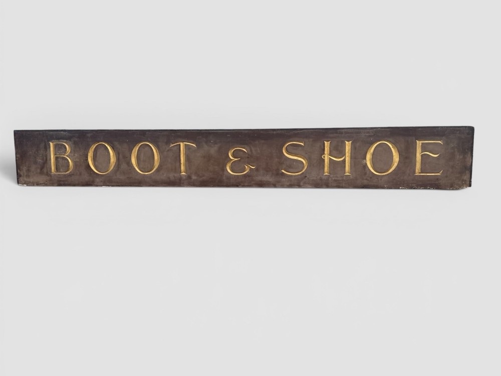 A long rectangular dark wooden sign with incised serif letters spelling DEPARTMENT gilded in gold leaf. View II