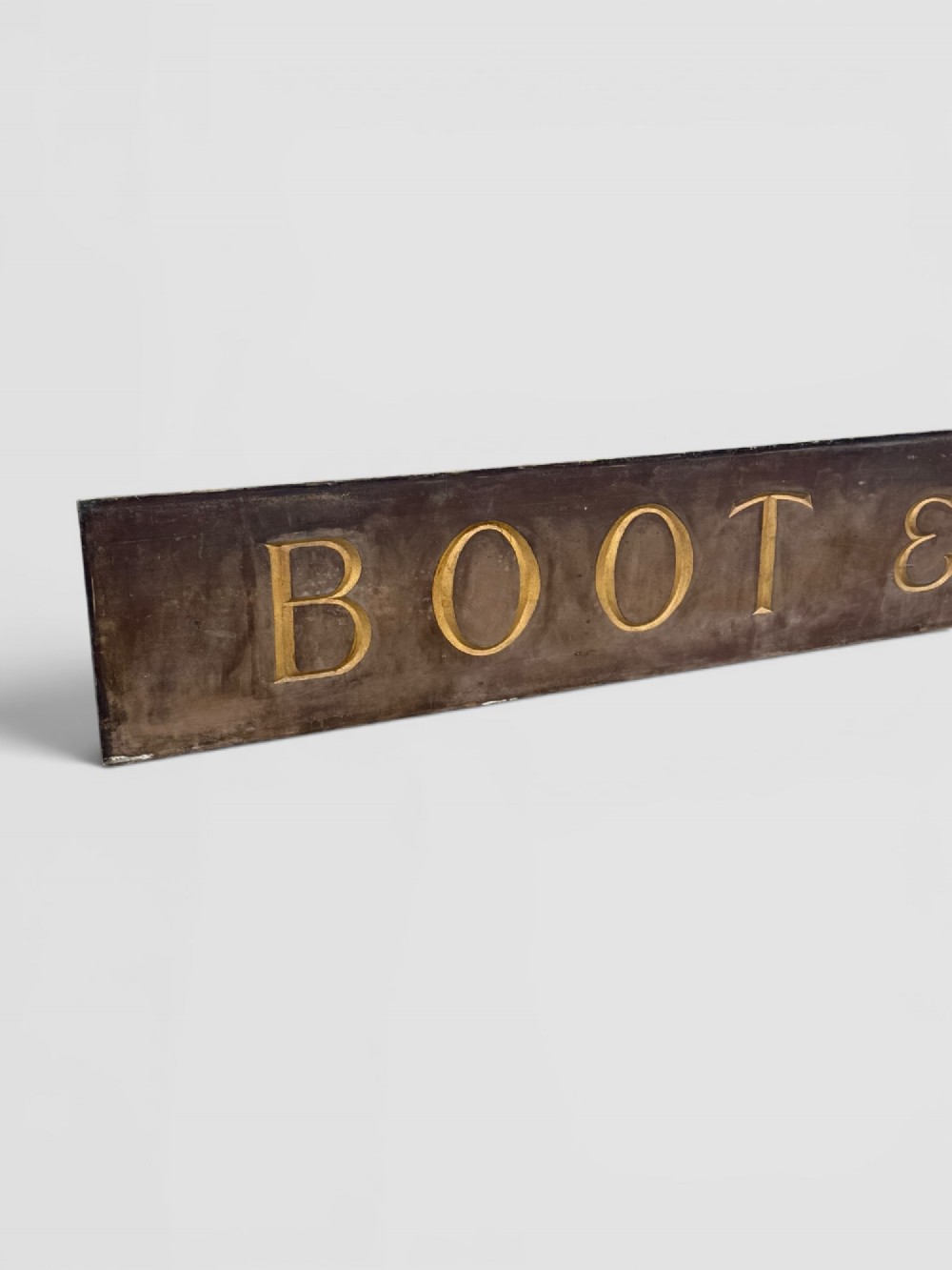 A long rectangular dark wooden sign with incised serif letters spelling DEPARTMENT gilded in gold leaf. View III