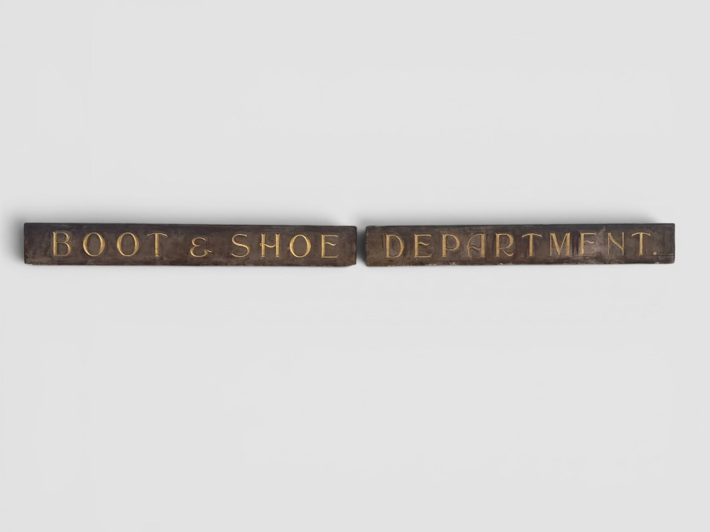 A long rectangular dark wooden sign with incised serif letters spelling DEPARTMENT gilded in gold leaf. View V