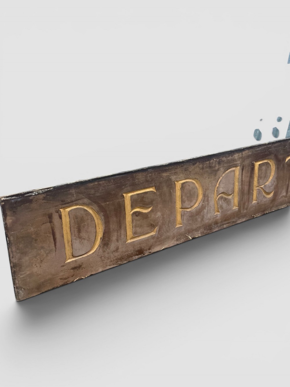 A long rectangular dark wooden sign with incised serif letters spelling DEPARTMENT gilded in gold leaf. View VI