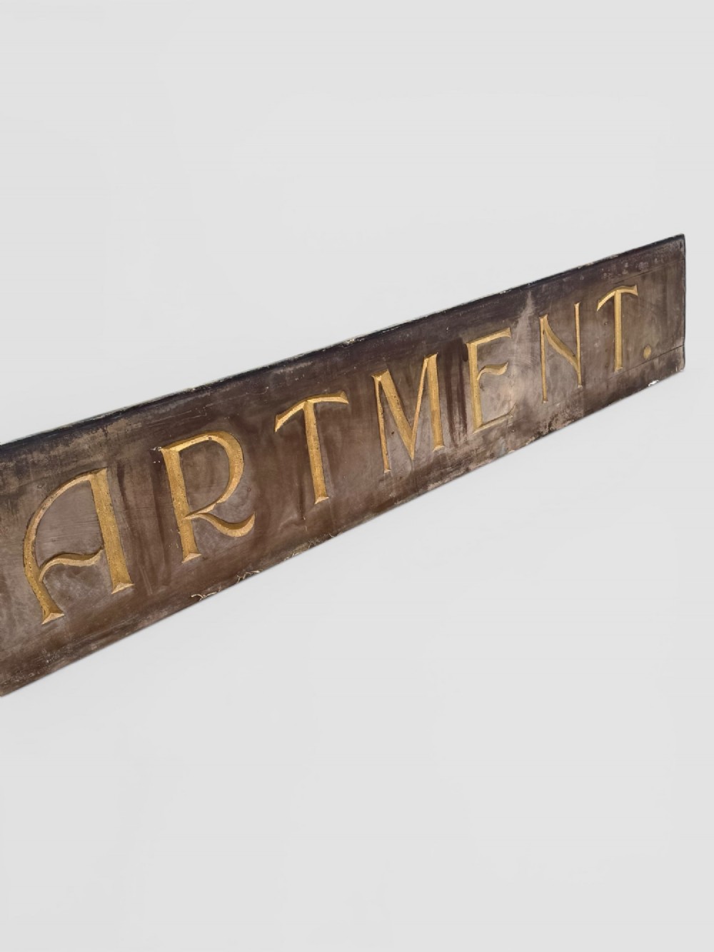 A long rectangular dark wooden sign with incised serif letters spelling DEPARTMENT gilded in gold leaf. View VII