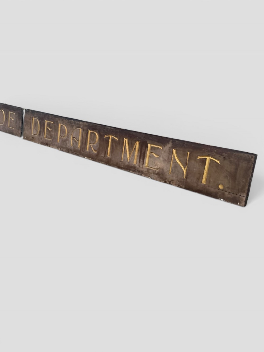 A long rectangular dark wooden sign with incised serif letters spelling DEPARTMENT gilded in gold leaf. View VIII