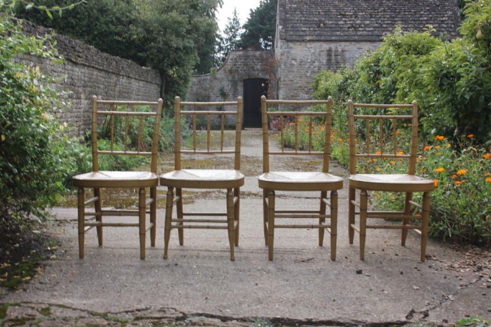 A set of four matching faux bamboo side chairs featuring turned timber frames and woven cane seats.