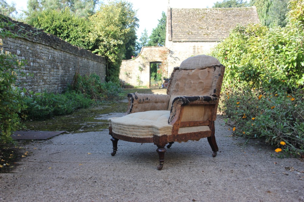 A Victorian armchair frame stripped to its base hessian upholstery, featuring turned mahogany front legs on brass castors.