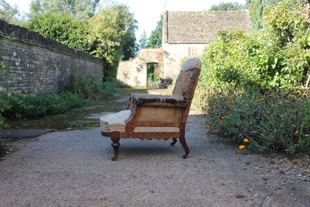 A Victorian armchair frame stripped to its base hessian upholstery, featuring turned mahogany front legs on brass castors. View II