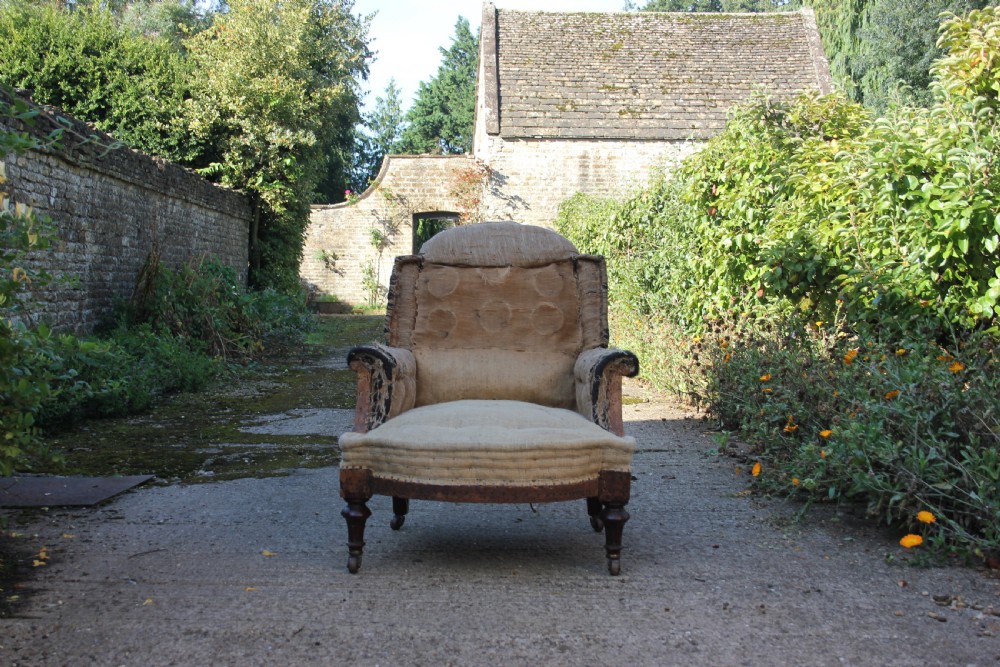 A Victorian armchair frame stripped to its base hessian upholstery, featuring turned mahogany front legs on brass castors. View III