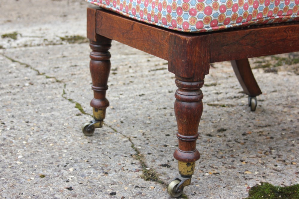 A 19th-century Victorian turned mahogany slipper chair with a spindle back and patterned upholstered seat resting on turned legs with brass castors. View IV