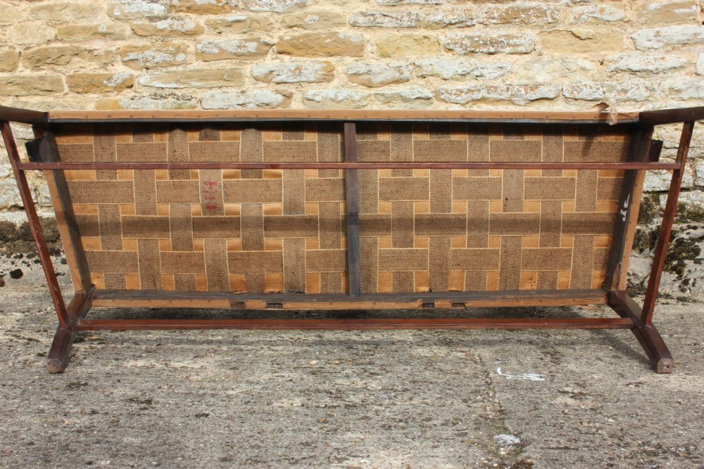 A 19th century mahogany triple shield back settee with carved splats, curved arms, and an upholstered seat cushion. View VII