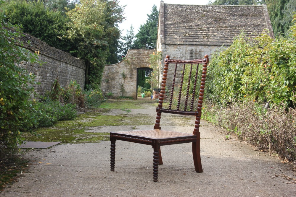 A 19th-century dark rosewood side chair featuring lathe-turned bobbin legs and backrest spindles with a woven cane seat.