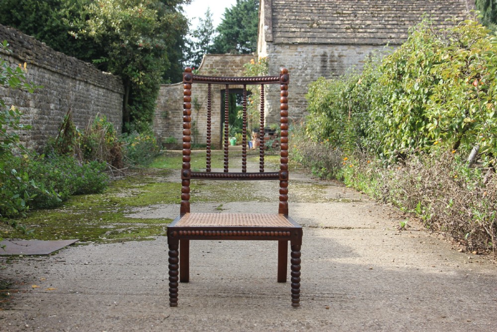 A 19th-century dark rosewood side chair featuring lathe-turned bobbin legs and backrest spindles with a woven cane seat. View III