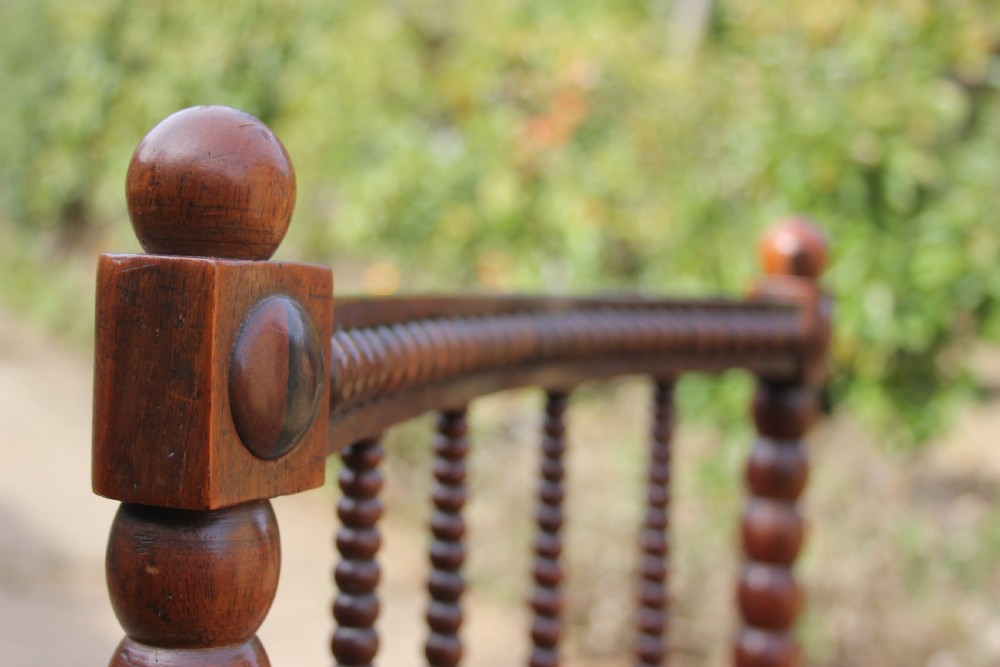 A 19th-century dark rosewood side chair featuring lathe-turned bobbin legs and backrest spindles with a woven cane seat. View VI